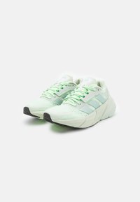 Un paio di sneakers sportive di colore verde chiaro con suole nere, tomaia in rete e strisce del marchio, posizionate affiancate su sfondo bianco.