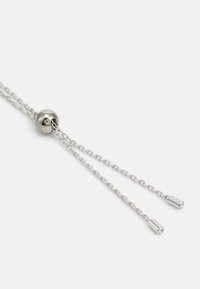 Catena metallica con una sfera liscia e rotonda, caratterizzata da due fili appesi con estremità cilindriche. Finitura argentata, che riflette la luce con una texture lucida.