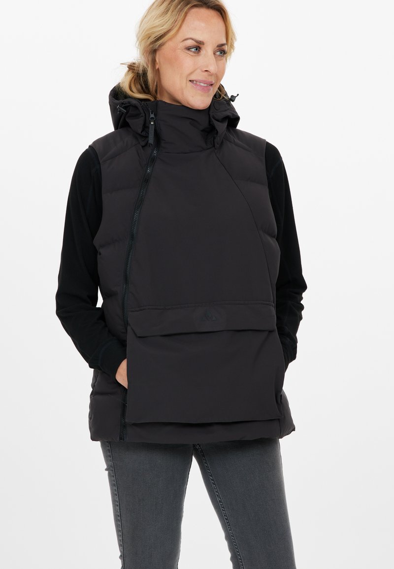 Schwarze isolierte Weste mit hohem Kragen, Reißverschluss und großer Vordertasche. Glattes Material mit matter Oberfläche; hat eine Kapuze.