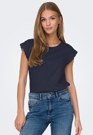 Marineblaues Kurzarm-T-Shirt mit Spitzenverzierung an den Schultern, kombiniert mit hellblauen hoch taillierten Jeans. Weiche Textur und lockere Passform.