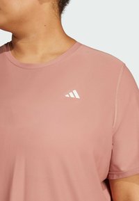 T-shirt sportivo rosa con un motivo testurizzato, scollatura rotonda e maniche corte. Presenta un logo bianco sul lato sinistro nella parte superiore.