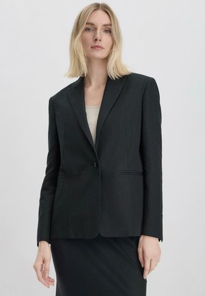 Zwarte op maat gemaakte blazer van gladde stof, met een enkele knoopsluiting, ingesneden revers en twee voorzakken met subtiele stiksels.