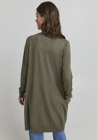 Olive green knitted cardigan, long-sleeved, mid-length, with side pockets and ribbed cuffs. Soft texture, simple design.