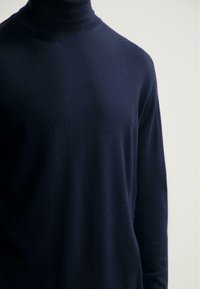 Námořnický rolák vyrobený z měkké tkaniny. Má slim fit, dlouhé rukávy a žebrovaný límec. Hladká textura s minimálním designem.