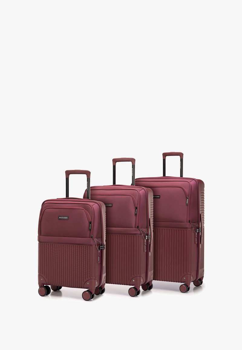 Tre valigie rigide color bordeaux con una texture scanalata, manici retrattili e quattro ruote. Le dimensioni variano, con tasche con cerniera sul fronte.