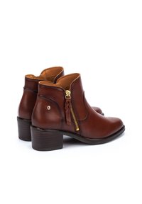 Botas de tobillo de cuero marrón con cremallera lateral de hardware dorado, punta redondeada y tacón de madera apilada.