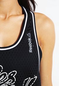 Schwarzes, luftiges Sporttanktop aus Mesh mit weißen Akzenten, featuring einem Reebok-Logo, breiten Trägern und lockerem Schnitt, der für Belüftung sorgt.