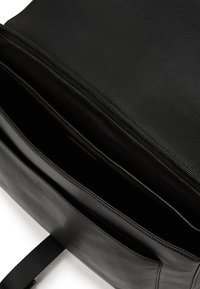 Borsa nera in pelle con una finitura texturizzata, dotata di più scomparti e un design semplice. L'interno è foderato per una maggiore protezione.