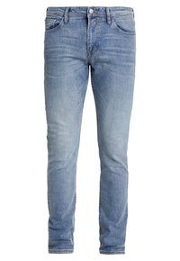 Světlé modré džíny z denimu s úzkým střihem. Mají standardní pětikapsový design, vybledlé praní a jemné žíhání přes stehna.