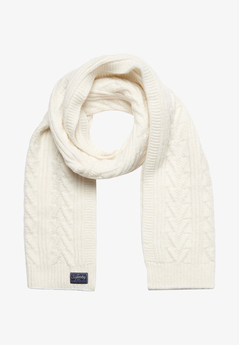 Écharpe en laine blanche tricotée avec motif torsadé et petite étiquette rectangulaire bleu foncé à une extrémité sur fond blanc.