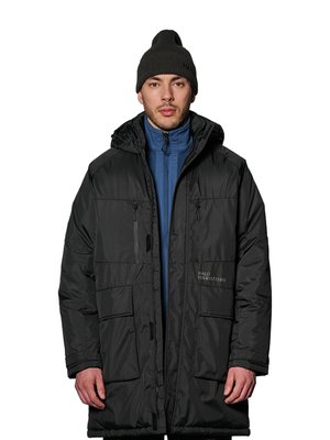 Man draagt een zwarte winterjas met meerdere zakken en een capuchon, daaronder een blauwe jas met rits en een zwarte gebreide muts.