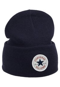 Bonnet en tricot bleu marine avec texture côtelée, présentant un patch rond blanc avec une étoile bleue et le texte "Converse All Star". Design classique.