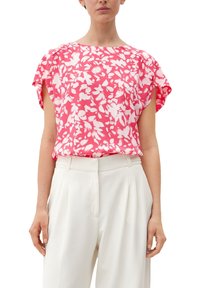 Top a maniche corte rosa con motivo floreale bianco, tessuto leggero, scollo rotondo, vestibilità leggermente ampia, abbinato a pantaloni bianchi a vita alta.
