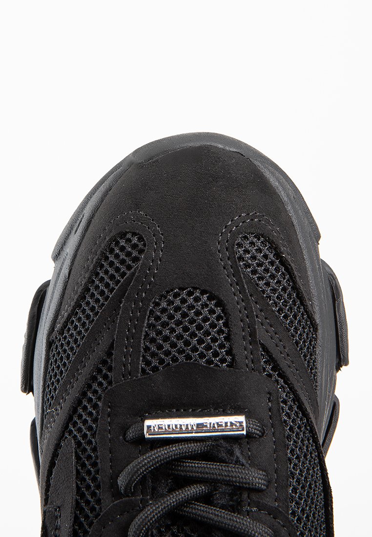 Czarne buty sportowe z siateczkową cholewką, z zamszowymi akcentami, grubą gumową podeszwą i płaskimi sznurowadłami. Posiadają teksturowane wzory i detale z logo.