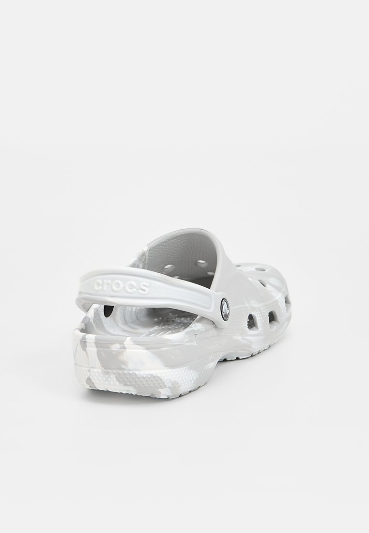 Graue Crocs mit einem Camouflage-Muster, aus leichtem Material hergestellt. Mit Belüftungslöchern, einem Rückenriemen und einer strukturierten Fußsohle.