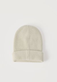 Μπεζ ριμπ πλεκτό σκουφί με διπλωμένη περιχειρίδα, απλωμένο επίπεδα σε λευκό φόντο.