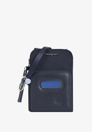 Compacte marineblauwe crossbodytas met voorvak, ritssluiting en metalen merklogo bovenaan.
