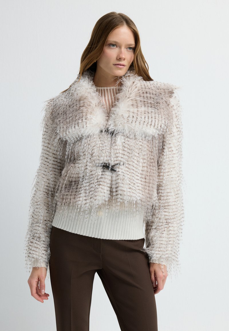 Chaqueta corta de piel sintética en beige con un patrón texturizado, que presenta un cuello de peluche, dobladillo acanalado y dos toggles negros en la parte delantera.