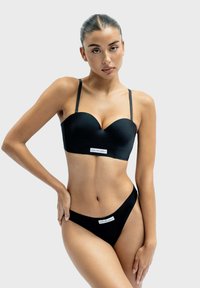 Czarny zestaw bikini z bezramkowym stanikiem o gładkiej teksturze i zaokrąglonej linii dekoltu, dopełniony pasującymi majtkami w niskim stanie.