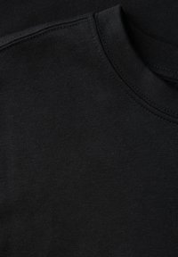 Schwarzes Baumwoll-T-Shirt mit Rundhalsausschnitt und glatter Textur. Nahtdetails sind sichtbar. Der Stoff hat eine gleichmäßige, einheitliche Farbe.