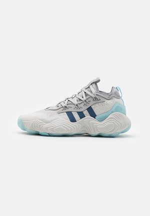 Baskets de sport en blanc, gris et bleu marine avec une tige texturée, trois accents en bandes et une semelle épaisse et ondulée de couleur bleue.