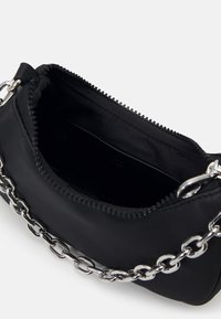 Sac à main noir avec une ouverture zippée, une bandoulière en chaîne argentée et une texture lisse. Intérieur doublé en tissu noir. Design simple et compact.