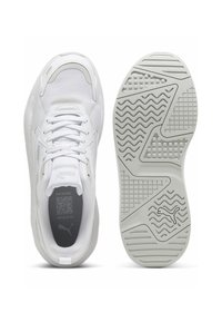 Chaussures de sport blanches avec une tige en mesh, une fermeture à lacets et des accents gris. La semelle présente un motif ondulé avec une texture antidérapante.
