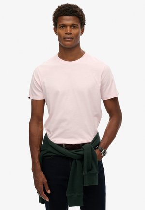 T-shirt a girocollo rosa chiaro in morbido cotone. Presenta maniche corte e una piccola etichetta con logo sulla manica sinistra. Abbinato a jeans scuri.