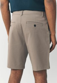 Khaki shorts lavet af glat stof, med en afslappet pasform, baglommer med knapper og en ufærdig søm.