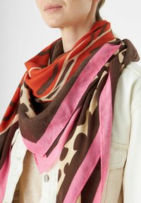 Écharpe multicolore avec des motifs abstraits dans des teintes de marron, rose, orange et crème. Fabriquée en tissu léger, elle se drape librement autour du cou.