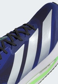 Running shoe with a navy blue mesh upper, silver three-stripe design, black laces, and green accents. Features LIGHTSTRIKE PRO midsole.