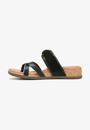 Black sandal featuring crisscross straps, a cork footbed, and a rubber outsole. Soft fabric accent on the instep for added comfort.