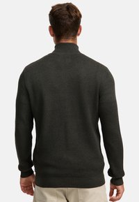 Mørkegrå strikket sweater med et tekstureret mønster, høj krave og ribbede manchetter. Har et slankt fit-design og sømløs ryg.