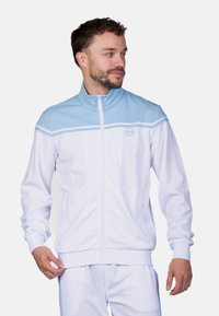 Weißer Zip-Up-Jacke mit hellblauen Akzenten und hohem Kragen. Enthält ein Logo und zwei horizontale Streifen über der Brust. Weicher Stoff. 