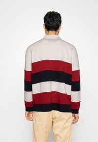 Pullover con colletto, caratterizzato da righe orizzontali in rosso, nero e beige. Realizzato in un materiale morbido con una vestibilità comoda.