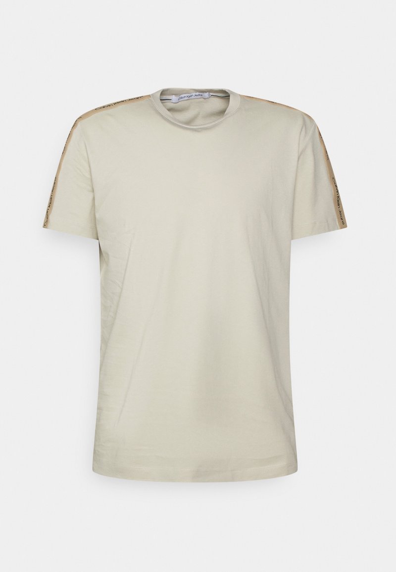 T-shirt beige a maniche corte con colletto rotondo e strisce beige con logo lungo le spalle e le maniche.