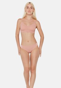 Ensemble de soutien-gorge et bikini rose clair sans coutures, avec des bretelles ajustables et un tissu doux. Design simple avec un minimum de matériel et une texture lisse.
