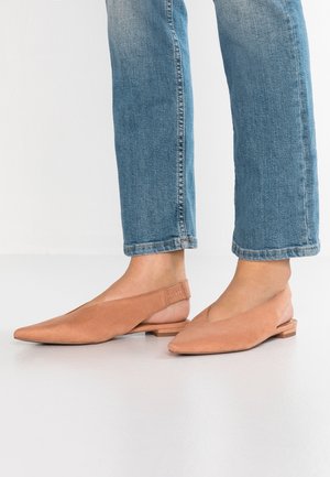 Płaskie buty na ramiączku z miękkiej, jasnobrązowej zamszowej skóry o spiczastym nosku i niskim drewnianym obcasie, z wycięciem w kształcie litery V z przodu.