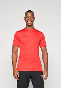 Rød Nike kortermet treningstrøye med rund hals, med en svart logo på brystet og et glatt, lett stof.