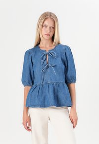 Svetlomodrý denimový top s nafúknutými rukávmi, okrúhlym výstrihom a viazaním vpredu. Peplum pás s nariasenými detailami.