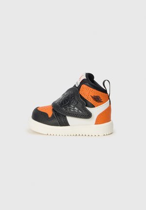 Sorte, oransje og hvite høye sneakers laget av lær, med en borrelåsrem, teksturerte detaljer og en gummi såle.