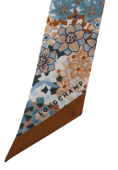 Silk floral scarf in turquoise, brown, and cream, featuring a vibrant flower pattern with the brand name "LONGCHAMP" printed at the bottom.