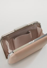 Rektangulär rosa clutchväska med ett glänsande silverlås, med ett fodrat inre och fack för organisering.