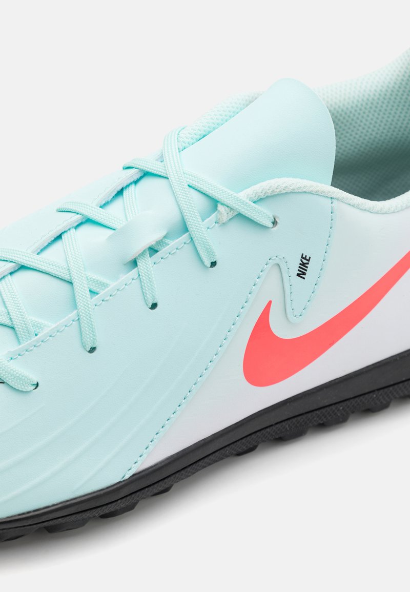 Zapatilla deportiva de color azul claro con una superficie texturizada, detalles en blanco, logo de Nike en rosa y cordones a juego. Presenta una suela exterior de goma negra.