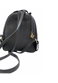 Zaino nero in pelle con finitura testurizzata, spallacci regolabili e accenti in hardware dorato. Presenta una chiusura con zip e un charm con logo.