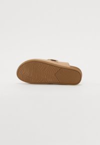 Sandal in suede color sabbia con suola in gomma e motivo a zig zag. Include una fascia singola sulla parte superiore.