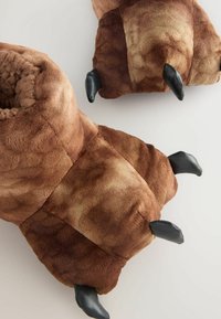Braune Plüsch-Tierpfotenschuhe mit schwarzen Klaudetails auf einem hellen Hintergrund, die weiches, texturiertes Material und gemütliche Innenteile zeigen.