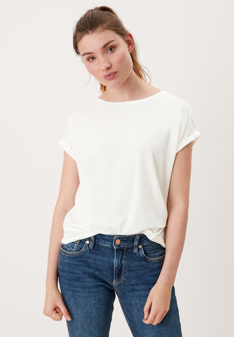 Witte T-shirt met korte mouwen en opgerolde mouwen, gemaakt van zachte stof, gecombineerd met donkerblauwe slim-fit jeans. Eenvoudig ontwerp en een ontspannen pasvorm.