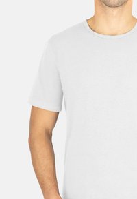 Kurzes weißes T-Shirt aus weichem Stoff mit rundem Ausschnitt und sauberer Naht, das einen lockeren Schnitt und eine glatte Textur aufweist.