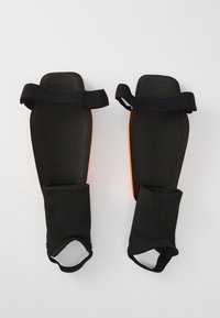 Mustad mustad mustad, millel on oranžid aktsendid, elastsete rihmadega kindla kinnituse jaoks. Sile tekstuur ja kokkuvam kuju mugavuse ja kaitse jaoks.